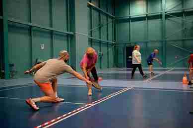 Pickleball Scotland: players participating in an indoor pickleball game on a blue court, showcasing the sport in Scotland.