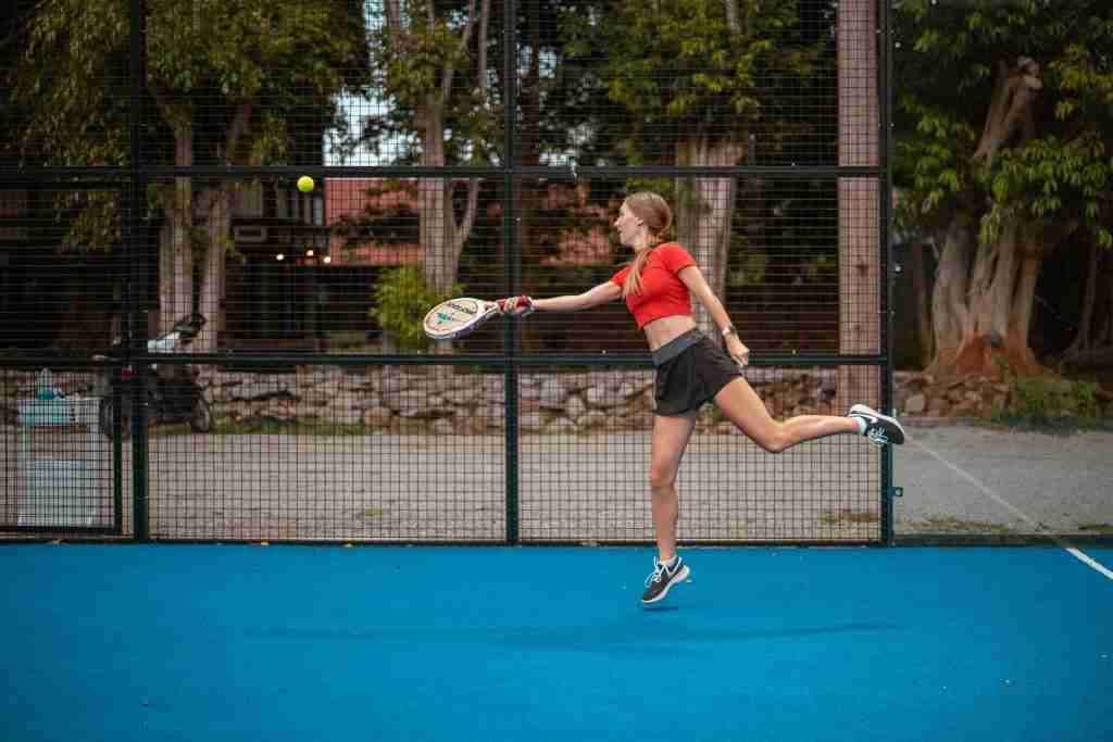 Female athlete playing on an outdoor court, highlighting action and movement in the debate of pickleball vs. paddle tennis.