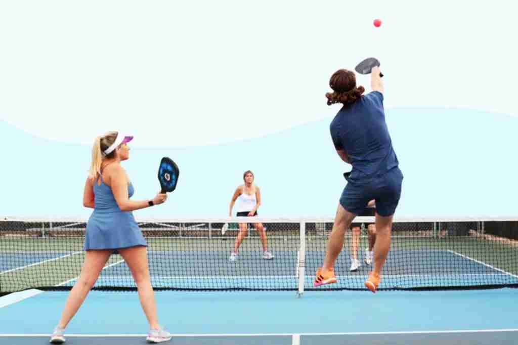 Pickleball players mid-game showcasing a dynamic lob shot in pickleball, with one player jumping to return the ball while teammates prepare at the net.