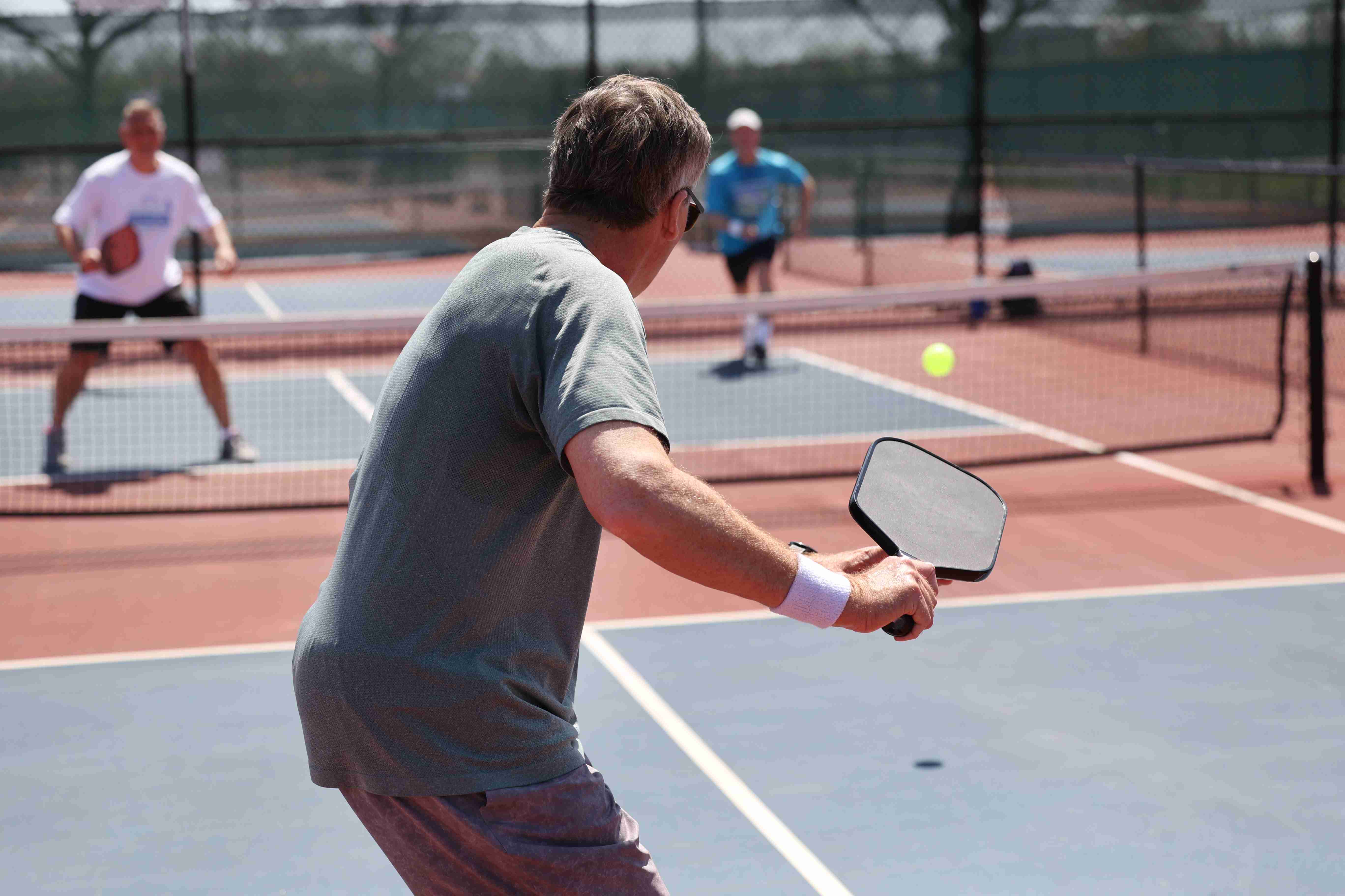 Older adults playing a competitive doubles match on an outdoor court, highlighting the importance of skill levels and accurate pickleball rating systems for fair play.