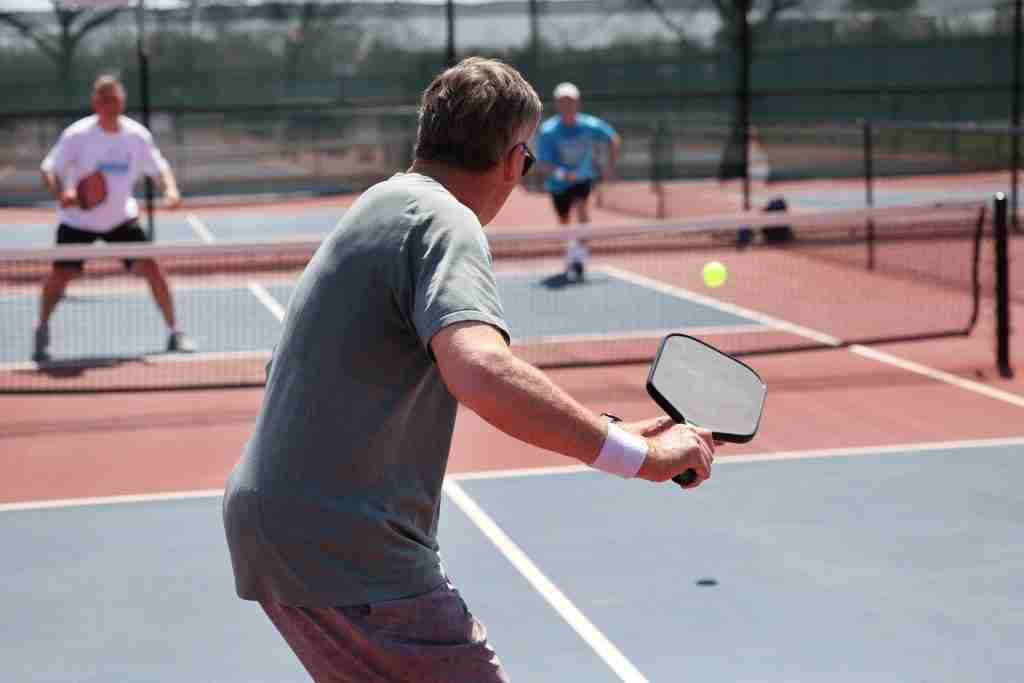 Players participating in a friendly doubles match during a 2025 summer pickleball camp & clinic on an outdoor court, highlighting real game practice and pro-level training.